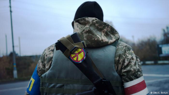 A government soldier mans a checkpoint in Donetsk. A peace sticker is visible on his back